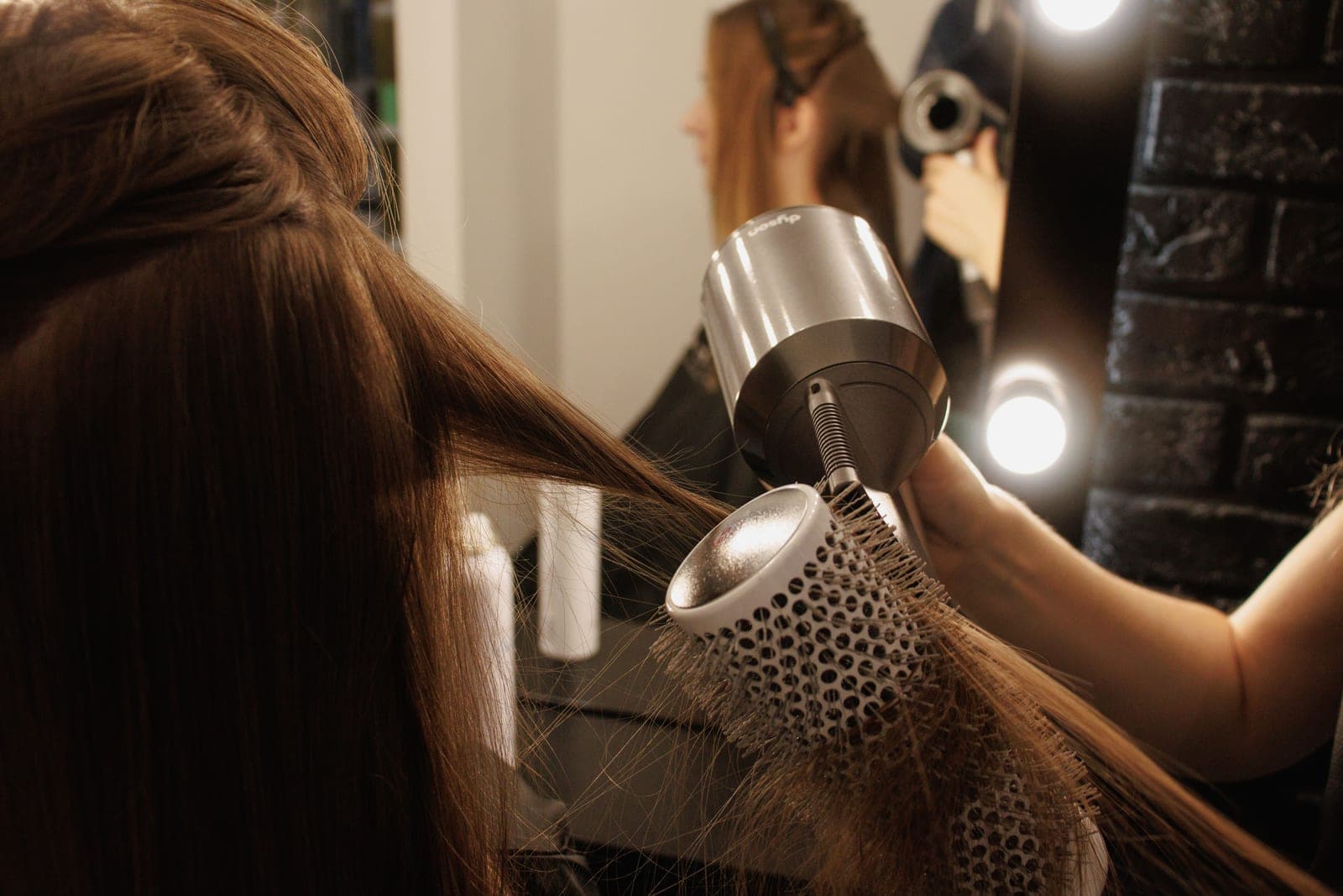 A hair dryer and styling tools lit against a dark background